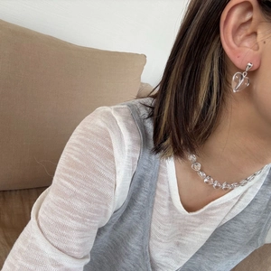 Detail van de transparante hartvormige hanger ketting en bijpassende oorbellen bij een model