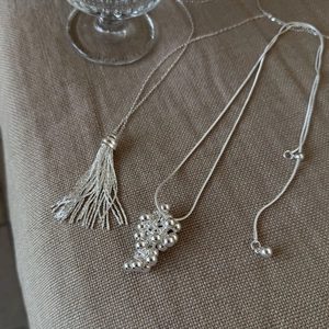 Detailed shot of silver tassel and grape cluster pendant with adjustable slider bead