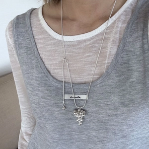 Close-up of a silver-tone necklace featuring a polished metal bead grape cluster pendant