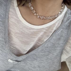 Detail van onregelmatige kristallen hartketting met metalen kralen bij vrouwelijk model