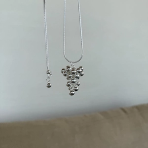 Detailed close-up of a silver grape cluster pendant with a fine snake chain necklace