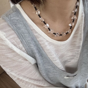 Detailopname van een kralenketting met transparante hartjes en zwarte kralen op een model