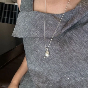 Silver grape cluster pendant necklace with hammered texture shown on a grey linen top