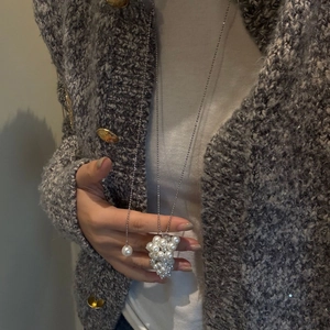 Detailed view of long pearl grape cluster pendant necklace on a knitted sweater