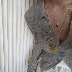Detail of layered silver necklaces with a yellow grape pendant and engraved rectangle bar