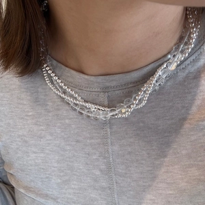 Close-up van een drielaagse kralenketting met zilveren en transparante kralen op model