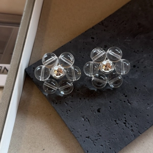 Detailopname van bloemvormige oorknopjes met heldere kralen op een donkere stenen houder