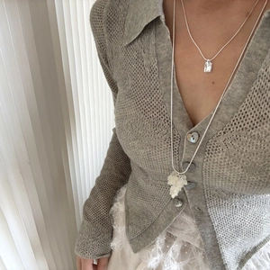 Detail of crystal grape cluster necklace and rectangular pendant layered on knitwear