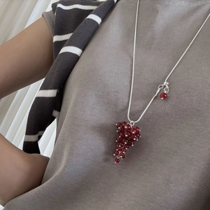 Close-up of a long grape cluster pendant necklace with deep red beads on a silver chain