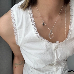 Detail der verstellbaren Kugelkette mit Herz-Kristallanhänger auf weißem Spitzenkleid