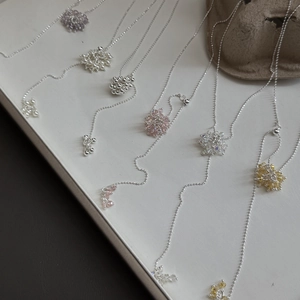 Detailed macro of silver grape cluster beaded necklaces with sunflower crystal pendants