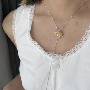 Detailed view of a silver Y-shaped necklace with amber crystal clusters on a lace top