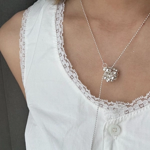 Detail of silver bead cluster pendant on a delicate ball chain worn over lace