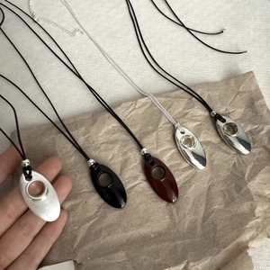 Detailed view of minimalist oval teardrop pendants in silver, black and brown finishes