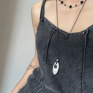 Detail of silver water-drop pendant and beaded choker layered on denim outfit