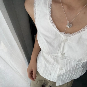 Detail shot of a silver floral cluster Y-shaped necklace worn on a white lace vintage top