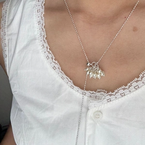 Detail of silver beaded Y-necklace with elegant white pearl cluster on female model
