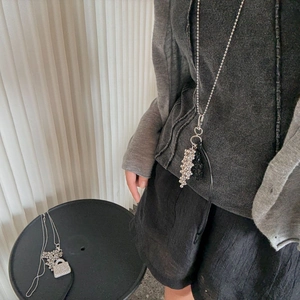 Detail view of long water bottle pendant necklace with rhinestones on black sweater