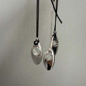 Detail of silver oval hollow pendants with polished and brushed matte finish on chains