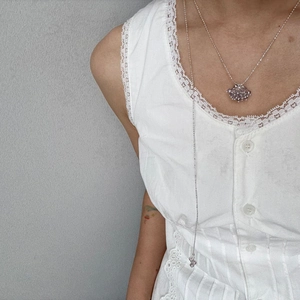 Detailed view of silver crystal grape cluster necklace and beaded long body chain on model