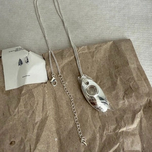 Detailed view of silver water drop pendant with hollow center on long sweater chain