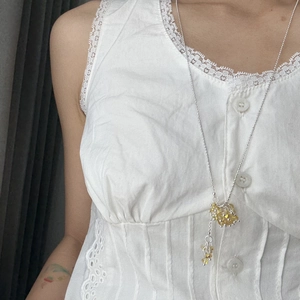Close-up of silver chain necklace with yellow crystal cluster and metallic tassels on lace
