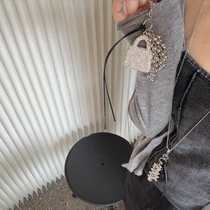 Detail of a sparkling rhinestone mini bag pendant necklace worn by a fashion model