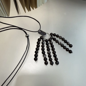 Detailed view of handmade black stone claw necklace with adjustable woven cord strap