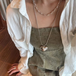 Layered silver necklace set with large heart pendant and beaded chains on model