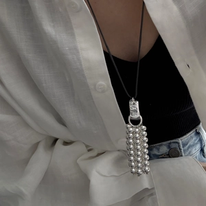 Minimalist silver bead fringe pendant necklace with black cord shown on clothing
