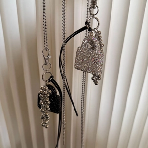 Detail of silver beaded chain with black heart pendant and sparkling purse charm