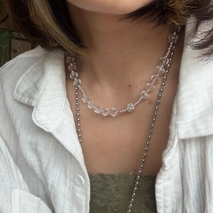 Detail of double-layer beaded necklace featuring crystal beads and silver flower charm