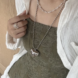 Detail of metal heart pendant necklace and faceted crystal beads on a female model