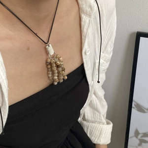 Detail of natural stone tassel pendant necklace with brown beads and silver hardware
