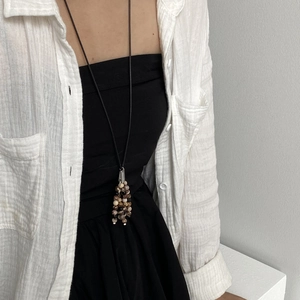 Detail of handcrafted natural stone tassel pendant necklace on a long black cord cord