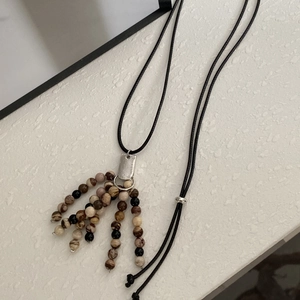 Close-up of long tassel pendant necklace with natural stone beads and silver metal plaque