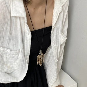 Detail view of a long vintage tassel necklace featuring natural stone beads on a model