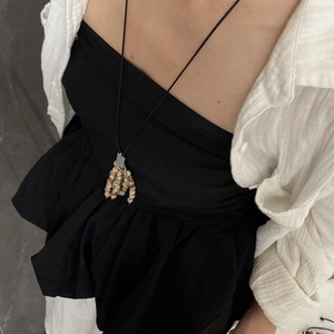 Detail of long tasseled natural stone necklace with wood beads on model's neck