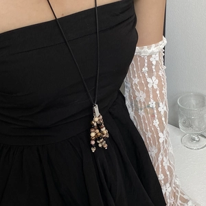 Close-up of a natural stone beaded tassel necklace on a model with lace gloves