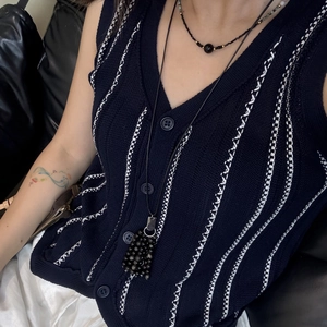 Close-up of titanium heart necklace and black bead choker on blue knit vest