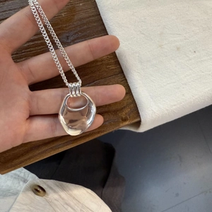 Close-up of heart-shaped liquid metal pendant on a silver necklace held by hand
