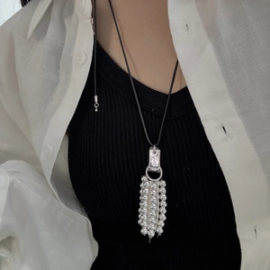 Detail of beaded metallic tassel long necklace on model wearing a white linen shirt