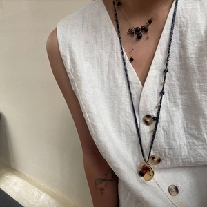 Layered tiger eye bead necklace and vintage snake chain on a white linen garment