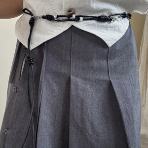 Detailed view of hand-knotted black cord waist chain with metallic bead accents on a model