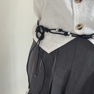 Detail of hand-woven black cord waist belt with silver metal beads and white pearls