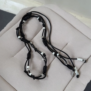 Handcrafted black braided cord necklace with white beads and metallic rivet accents