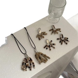 Ethnic earth-toned natural stone beaded necklace and earring set on white textured surface