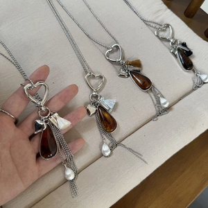 Detail of heart clasp, amber resin droplet, and silk tassels on long sweater necklace