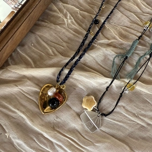 Detail of woven rope necklaces with heart pendant, ceramic stars, and fringe accents