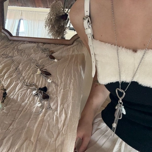 Detail of long sweater chain with heart clasp, brown teardrop pendant and tassels